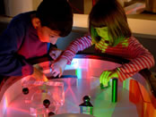 Kids play with a light table at the Science Museum