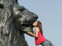 Woman kissing one of the four bronze lions by Edwin Landseer. ©VisitBritain / James McCormick