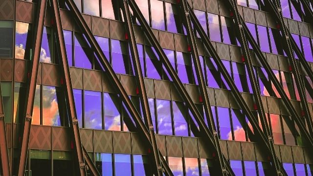 Glass windows of a building reflecting the purple sky and orange clouds.