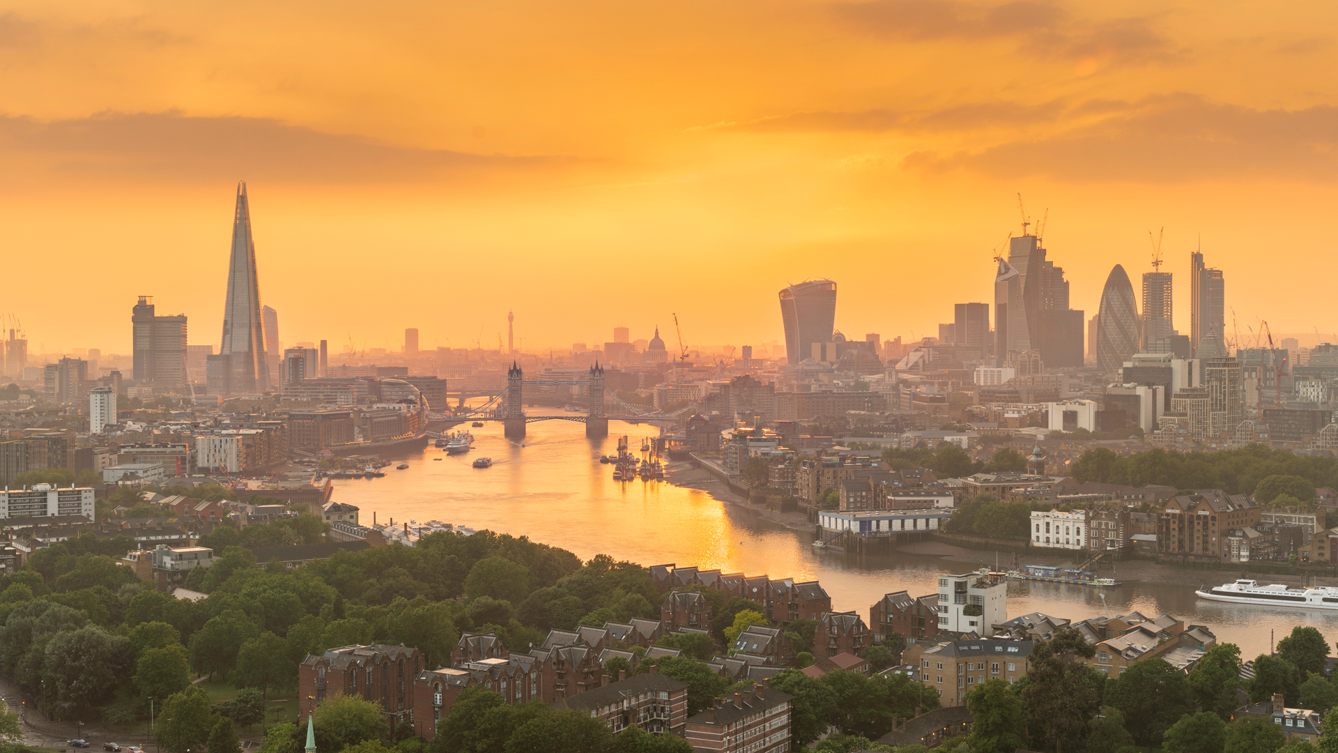 Sunset over the river Thames with orange tones and the city's skyscrapers in the background including The Shard 