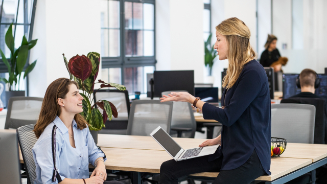 Two colleagues sitting down and chatting in a London office.