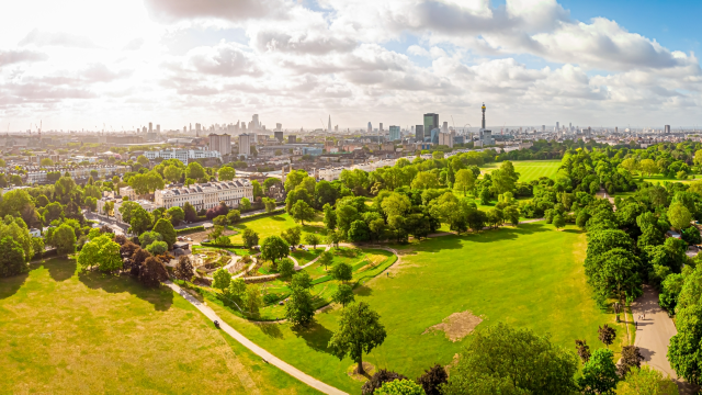 Two people sitting on Parliament Hill on a sunny day looking towards central London