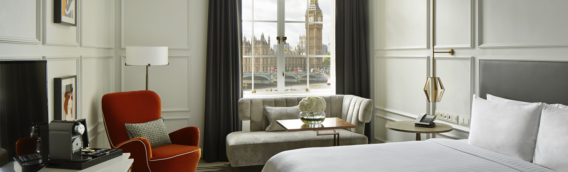 Bright hotel room with an elegant white interior, with a view of the Big Ben and Houses of Parliament.