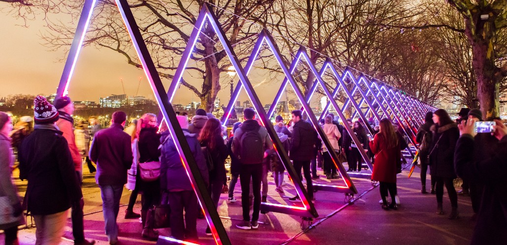 Lumiere London light festival featuring colourful triangles at night with crowds attending.