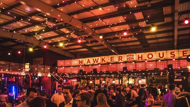 Hawker House from the inside, a big food hall decorated with red and yellow light bulbs on the ceiling