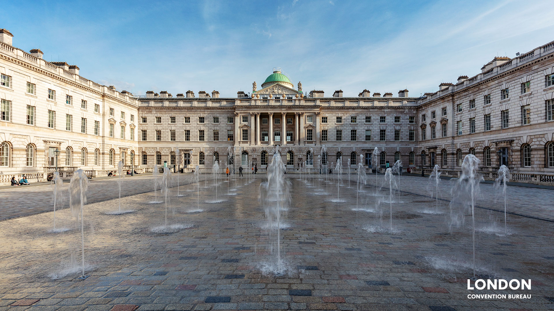 Small symmetrical fountains from the ground are surrounded by the Somerset House building.