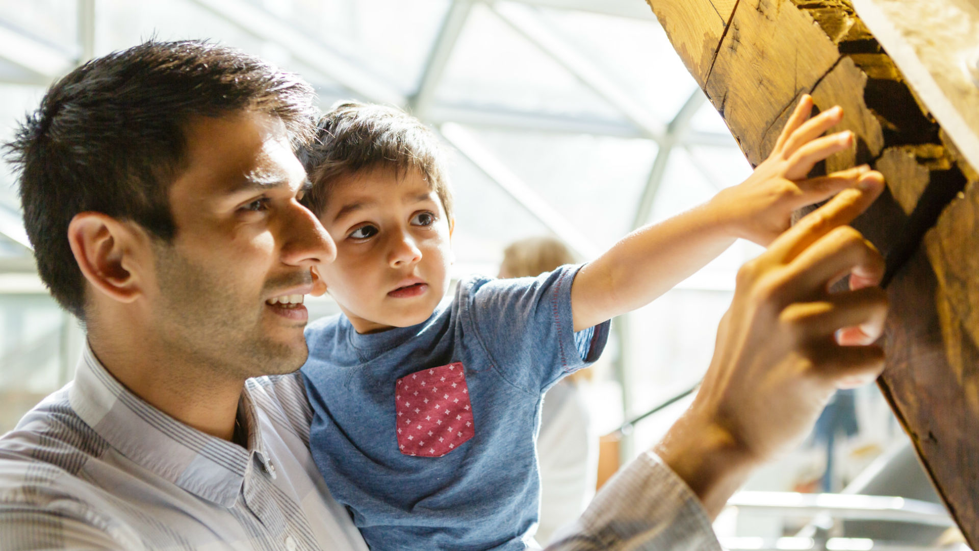 Father and child touching a wooden exhibit at the Cutty Sark.