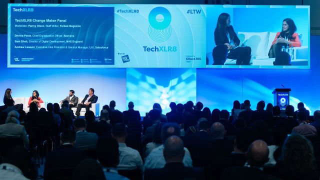 An audience watches a panel discussion on stage as part of London Tech Week.