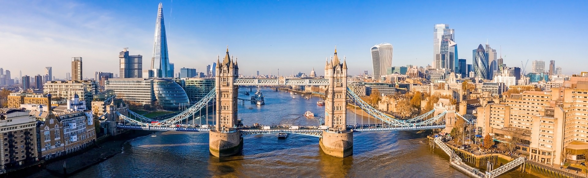 An aerial view of the river Thames on a sunny day with Tower Bridge, The Shard and the City of London