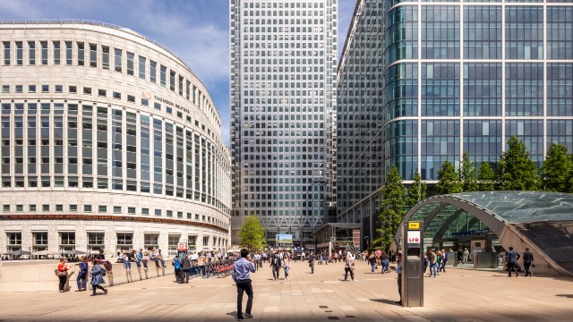 People stroll in front of skyscrapers and office buildings in Canary Wharf