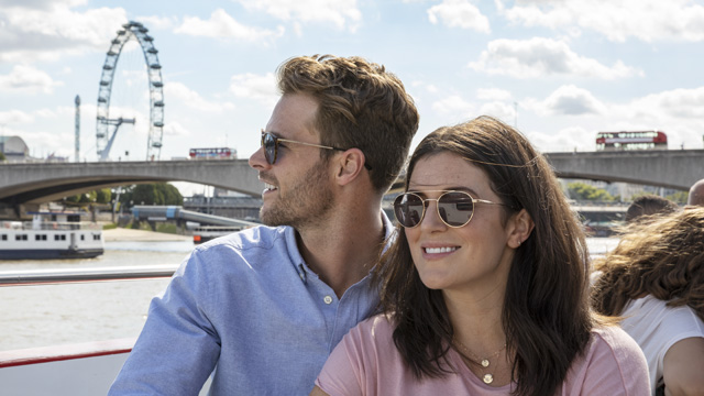 Un couple se tiennent côte à côte et se sourit lors d'une visite guidée de Londres avec le London Pass, tandis que l'on voit le London Eye à l'arrière plan.