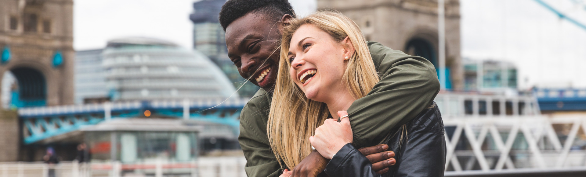 Explore the best of London. Copyright: Shutterstock. Image courtesy of Shutterstock. A couple laugh as they explore London with Tower Bridge in the background.