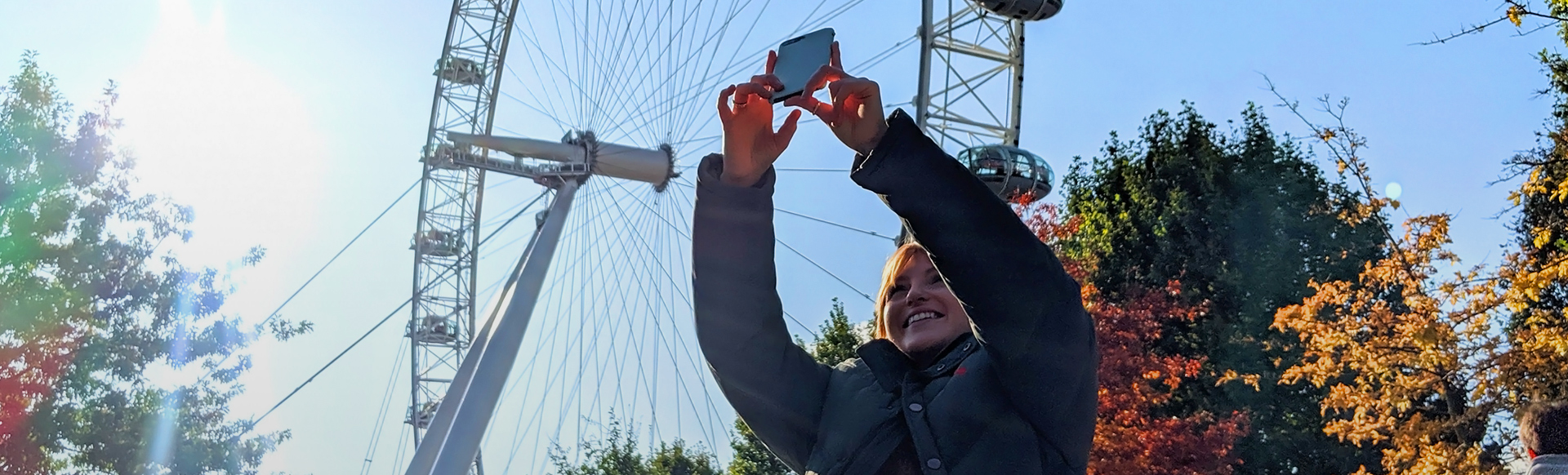 Let's do London. Image courtesy of TMW Unlimited. A woman takes a photo with her smartphone, with the London Eye in the background.