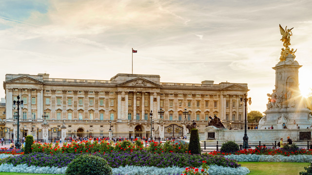The sun sets behind Buckingham Palace which is lit with a golden glow
