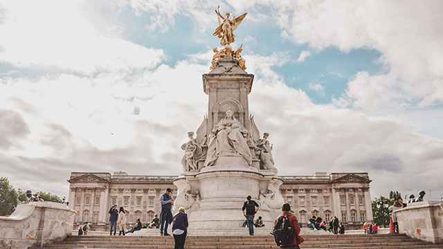 The Victoria memorial in front of Buckingham Palace with people of the steps.