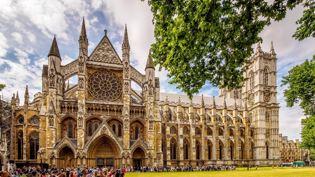 Crowds of people admire the grand exterior of Westminster Abbey on a sunny day