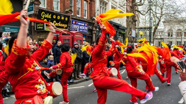Dancers dressed in bright red costumes dancing with chinese dragons on chinese new year in london.