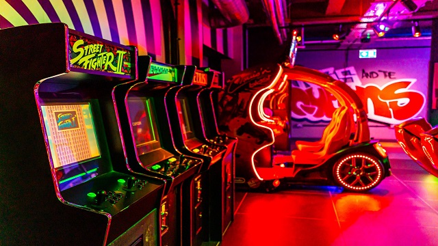 A vibrant room with neon decor and arcade machines and games
