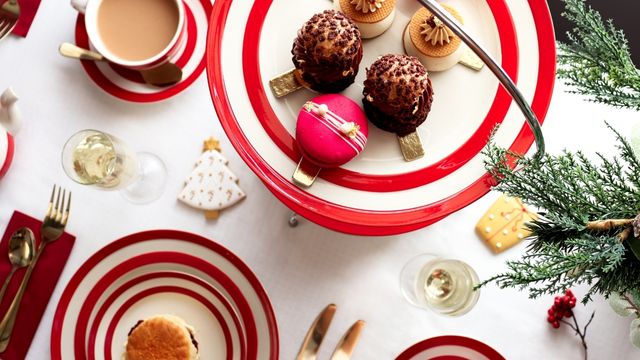 A festive table laid with vibrant plates with christmas themed sweet treats at the Biscuiteers Christmas afternoon tea in London.