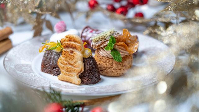 A white plate surrounded by christmas decorations with a pastry father christmas and chocolate yule log at the Conrad London Hilton afternoon tea.