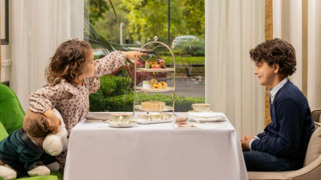 Two children sit at a table enjoying a festive afternoon tea at grosvenor house london.