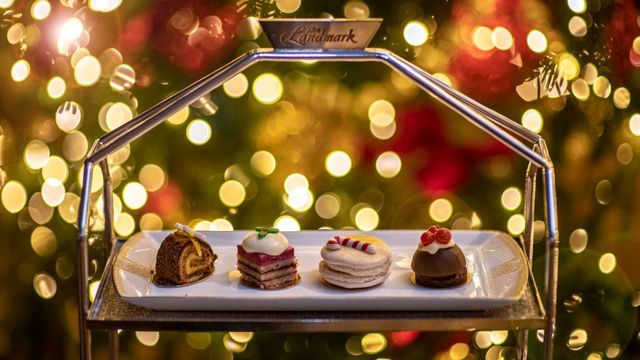 A place with christmas themed desserts including a mini christmas pudding and christmas macaroon surrounded by fairy lights. 