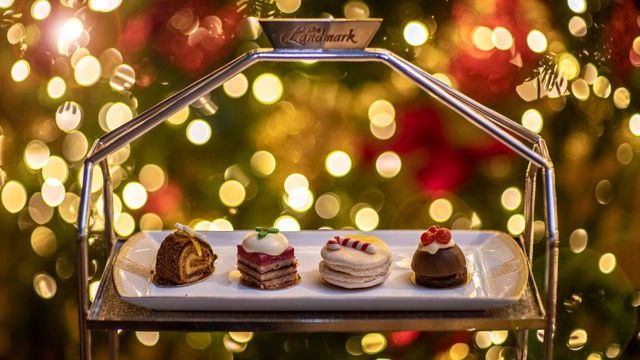 A place with christmas themed desserts including a mini christmas pudding and christmas macaroon surrounded by fairy lights.