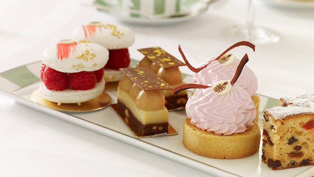 Seven small, colourful cakes on a green-and-white-striped plate.