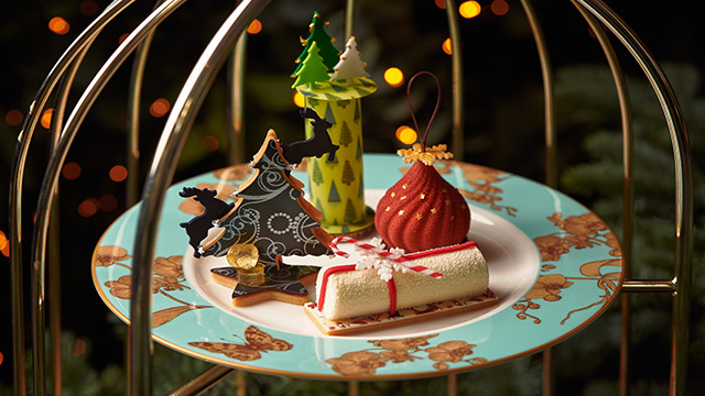 A selection of Christmas-themed cakes, including cakes resembling a Christmas tree, present and bauble, on a plate.