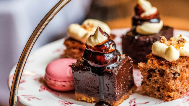 Une sélection de gâteaux, dont un macaron rose, des gâteaux au chocolat et une génoise, sur la plaque supérieure d'un présentoir à gâteaux.