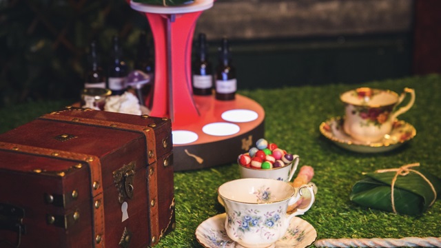 A treasure chest, traditional cups and saucers, and a cake stand with small bottles as part of the Arcane Afternoon Tea experience at the Wands and Wizard Exploratorium.