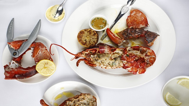 An aerial shot of plates of cooked lobster with mini bowls of warm butter