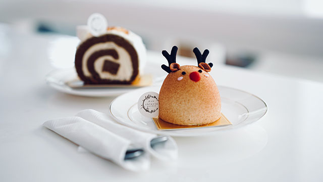 Un gâteau en forme de renne sur une assiette et une table blanche