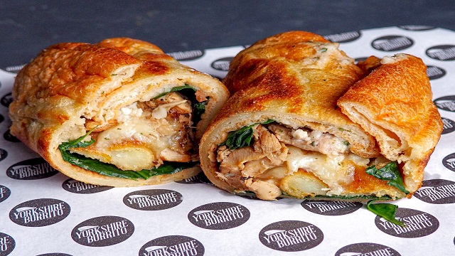 A yorkshire pudding wrap with chicken, roast potatoes, gravy and stuffing