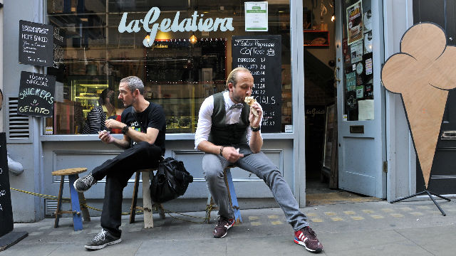 Two men eating ice cream outside an ice cream parlour