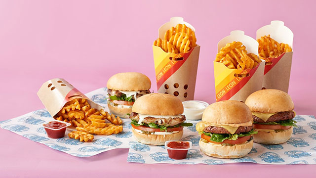 A selection of burgers and fries in front of a pink background