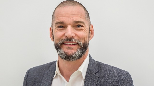 Fred Sirieix is smiling to the camera while his portrait is taken.