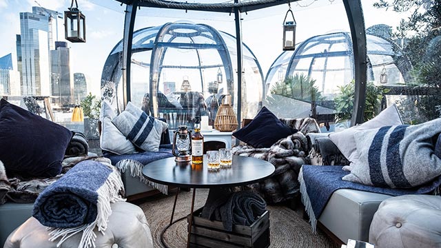 Looking out from one of the Aviary igloos, with rugs, lanterns and a table with two bottles and glasses of whisky.