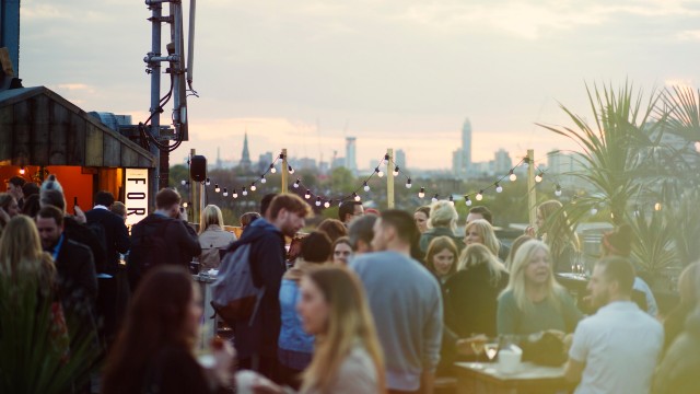 A busy rooftop bar with fairy lights and stunning views across London's skyline.