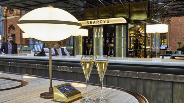 Two glasses of champagne beside a lamp in a champagne bar in st pancras. 