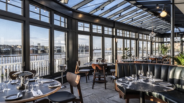 Large open planned conservatory dining toom with tables, chairs and booths, overlooking the river