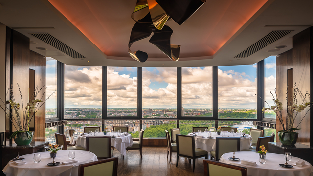 A landscape shot of a restaurant with floor to ceiling windows, overlooking the London skyline