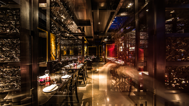 Darkly lit interior with dark wooden tables and chairs at Hakkasan Hanway Place.