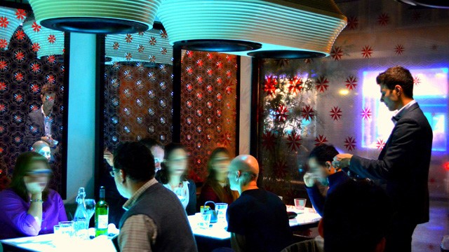 Tables of diners being served by a waiter in the high-tech Inamo restaurant