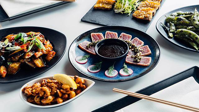 A selection of sushis and asian tapas is presented on a table.
