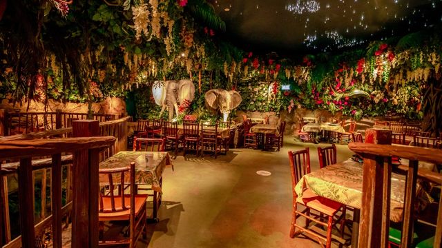 Tables and chairs surrounded by plants and animals at the jungle-themed restaurant Jungle Cave in London.