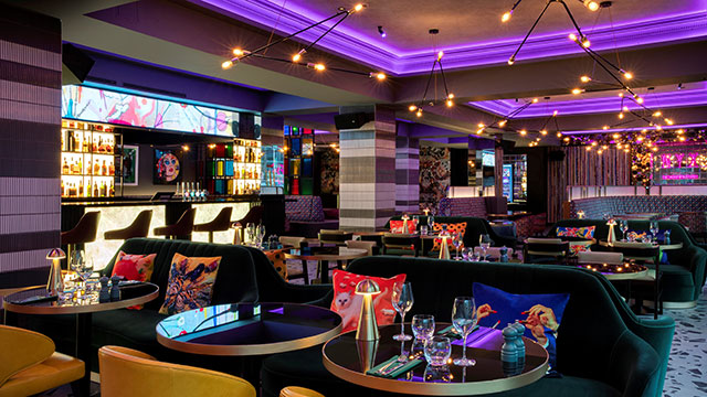 The colourful and eclectic interior of the Eat Drink & Play bar and restaurant at the NYX Hotel in the evening.