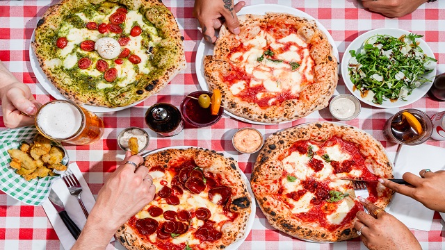 High angle shot of different pizzas on a red and white table cloth