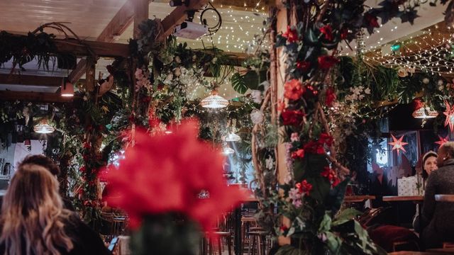 A winter rooftop bar in brixton is covered in green and red christmas foliage.