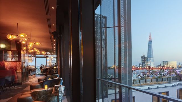 A parallel image of Savage Garden rooftop bar in London, showing the warm orange interiors and the open rooftop near the shard.